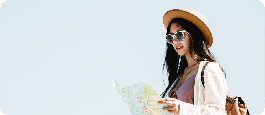 Young woman backpacker with hat looking at map while traveling
